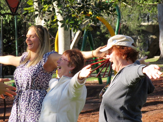 Three women tretching and laughing in a park