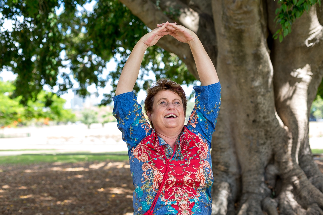 A woman stretching her arms above her head in a laughter yoga pose