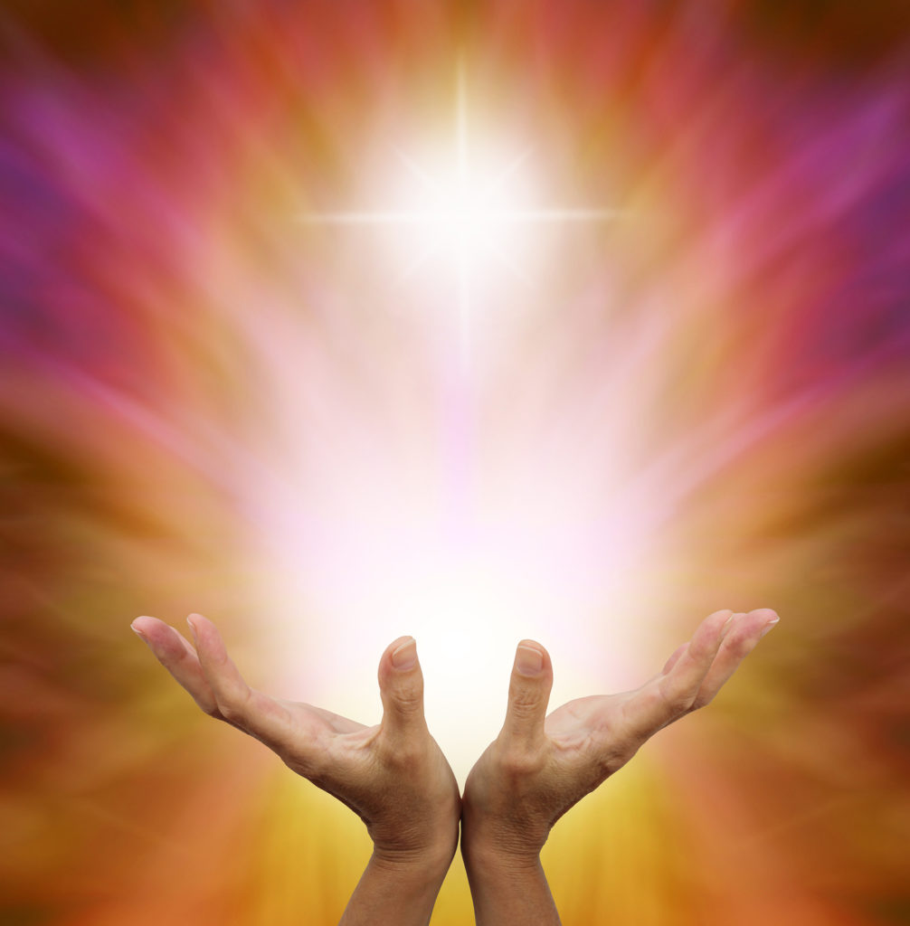 Healer's hands outstretched with burst of white energy above on a golden magenta background