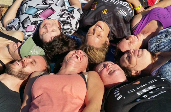 seven people lay in circle, heads together, laughing
