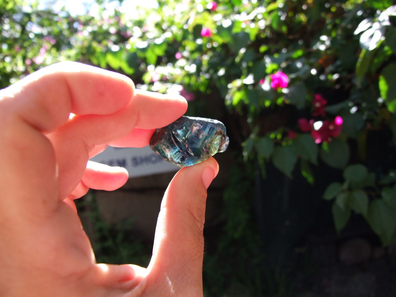 A gemstone held between thumb and forefinger, found in Queensland gemfields