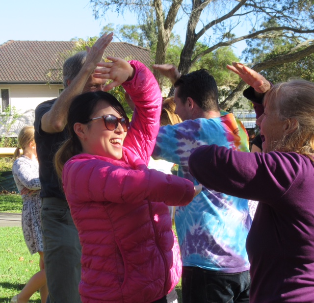 Two women facing each other laughing with people doing same in background