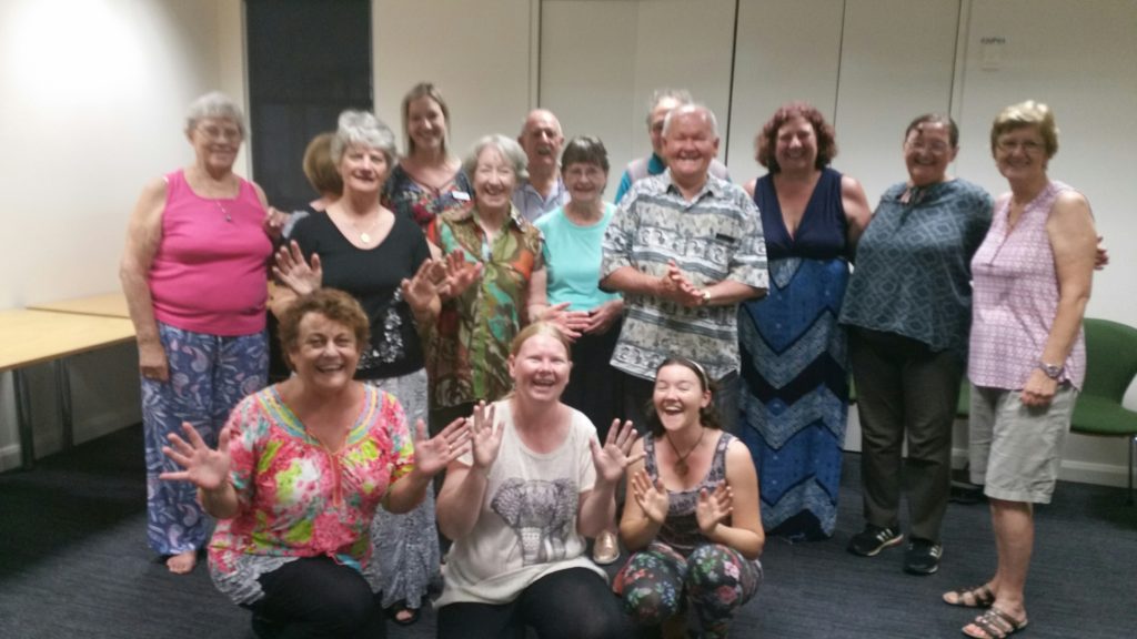 A group of people in a room standing together smiling