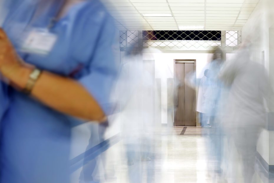 Nurses in a hospital ward, the image is blurred, suggesting rushing.