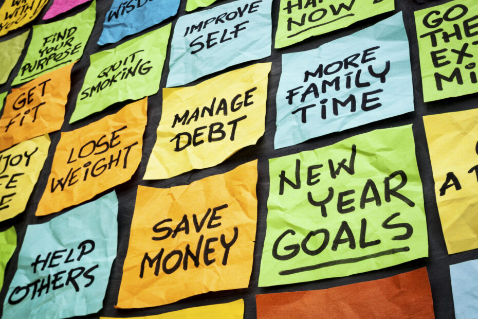 a wall of sticky notes with New Year goals - or resolutions - handwritten on them including save money, manage debt, more family time, get fit, lose weight, find purpose.