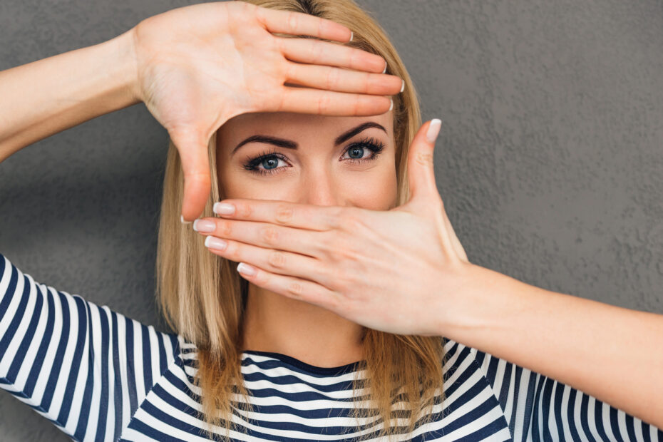 Woman holding her hands over her face while exposing her eyes