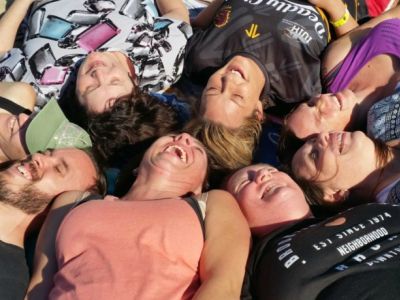 seven people lay in circle, heads together, laughing