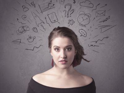 A dark brown haired young woman with thoughts in her head illustrated by question mark, rocket, money, coffee, clock, email, social life icons drawn on the background wall concept.