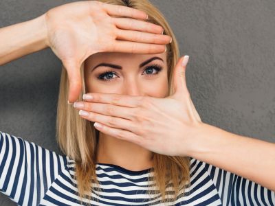 Woman holding her hands over her face while exposing her eyes