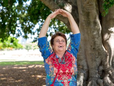 A woman stretching her arms above her head in a laughter yoga pose