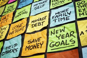 a wall of sticky notes with New Year goals - or resolutions - handwritten on them including save money, manage debt, more family time, get fit, lose weight, find purpose.