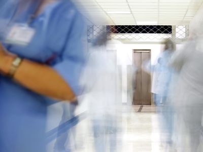 Nurses in a hospital ward, the image is blurred, suggesting rushing.
