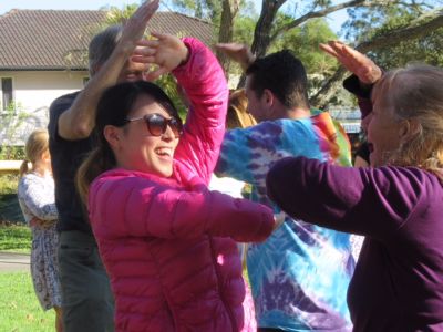 Two women facing each other laughing with people doing same in background