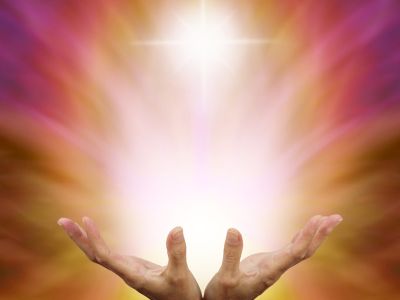 Healer's hands outstretched with burst of white energy above on a golden magenta background